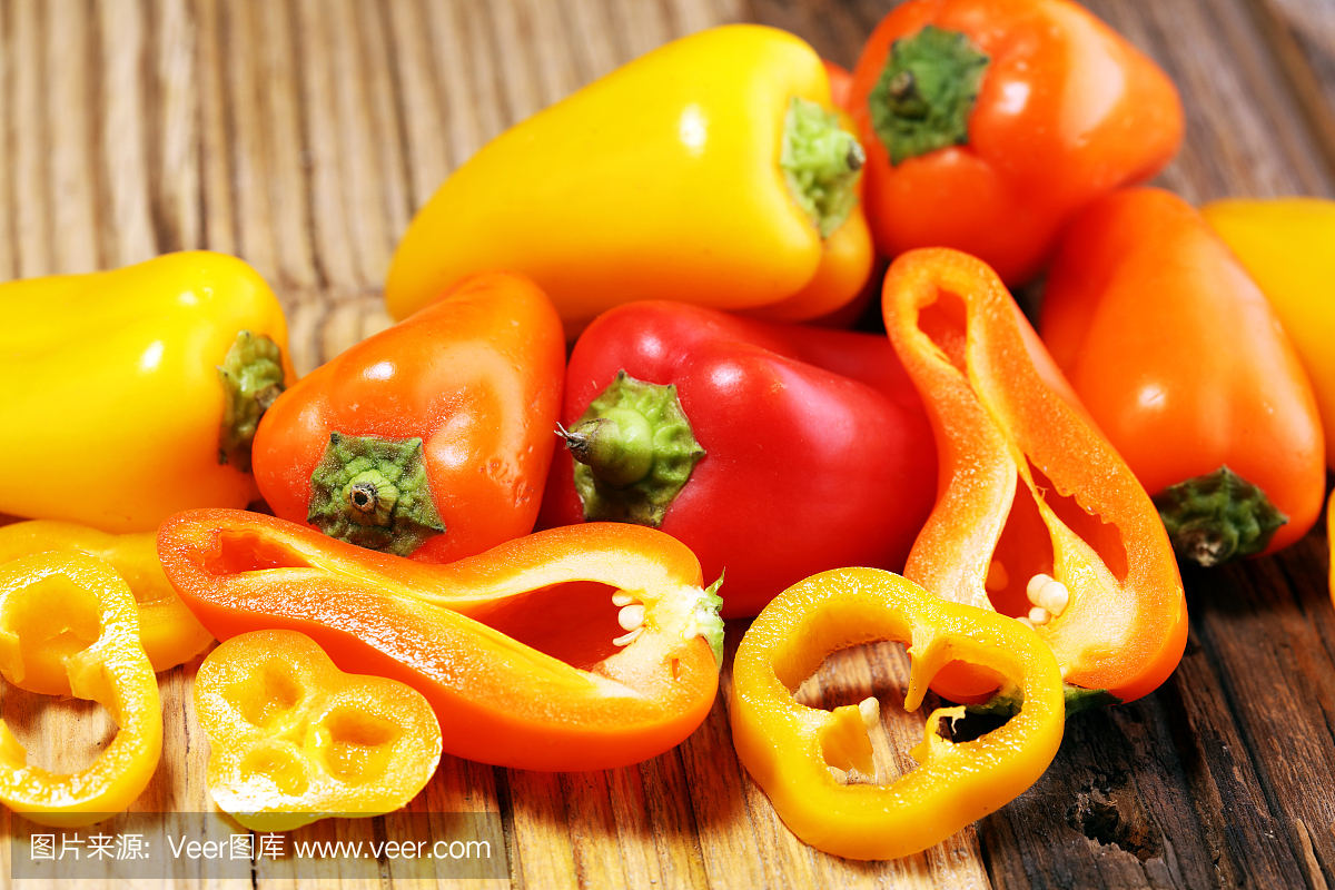 新鲜的红色,黄色和橙色的甜椒在木质背景上。生的蔬菜